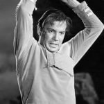 William Shatner as Captain James Kirk, in grayscale, holding a rock over his head with a strained expression.